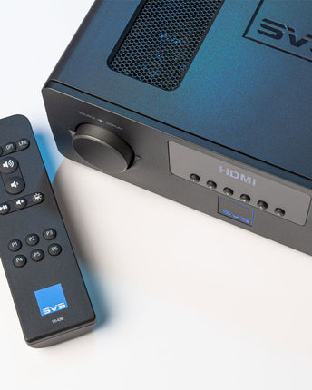 SVS Prime Wireless Pro Soundbase, vedere de sus-lateral cu grila de ventilație și telecomanda sprijinită în față