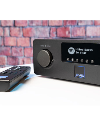 SVS Prime Wireless Pro Soundbase, aparatul pe un blat, cu display-ul afișând o piesă redată prin Spotify