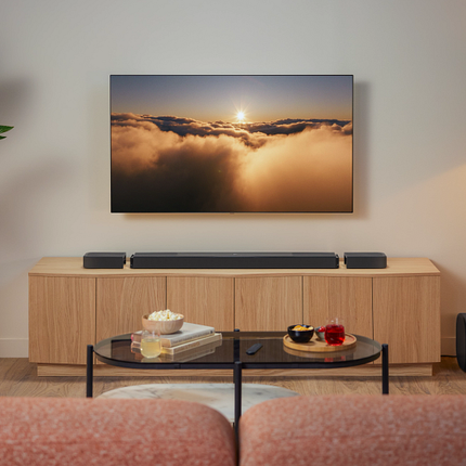 JBL Bar 1300MK2 върху шкаф със субуфера до него във всекидневна