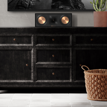 Boxa Klipsch R-50C asezata pe un bufet, sub un televizor montat pe perete