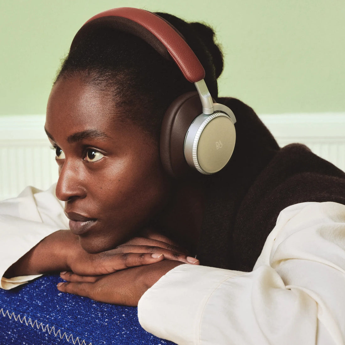 Beoplay H100 în finisaj Sunset Apricot, pe fundal neutru.