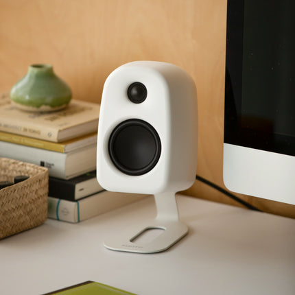 Boxă Kanto Audio UKI White pe un stand de birou Kanto, lângă un monitor