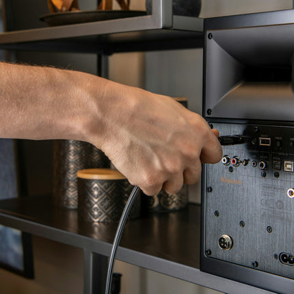 O mana conecteaza cablul HDMI in spatele boxei active Klipsch The Fives